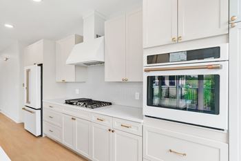 A white kitchen with a black stove top and a white oven with a window.